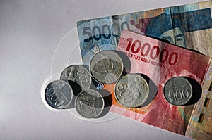 50000 and 100000 Indonesian Rupiah currency and some old Rupiah coins, on white background. The concept of saving and inflation