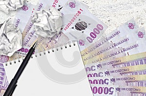 50000 Romanian leu bills and balls of crumpled paper with blank notepad. Bad ideas or less of inspiration concept. Searching ideas