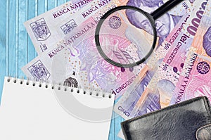 50000 Romanian leu bills and magnifying glass with black purse and notepad. Concept of counterfeit money. Search for differences