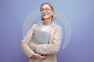 50s middle aged business woman in jacket mastering new profession using laptop on studio background with copy space