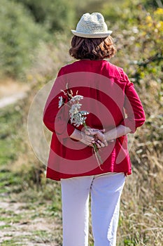 50s woman strolling around alone with field flowers