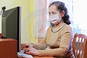 55-year-old senior woman working with face mask at home office
