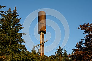 5G cellular antenna covered by a brown visual shield, installed on a wood power line monopole, sunny fall day