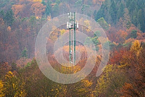 5G mobile phone tower and cellular mast jutting out of fall colored trees