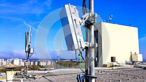 5G mobile telecommunication smart cellular radio network antennas on a mast on the roof broadcasting signal waves