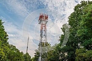 5G telecommunications tower and single cellular provider mast framed by trees