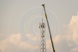 5G transmission tower is erected on a field with the help of a huge crane