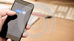 5G `wireless technology` slide button on smart phone device being turned on by the user in a close up office scene