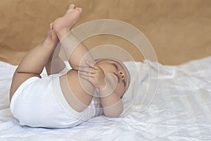 6-8-month-old baby boy lying playfully in bed