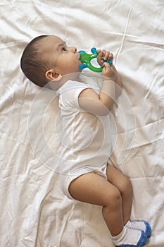 6-8-month-old baby boy lying playfully in bed. Charming 6-7 month little baby in white bodysuit