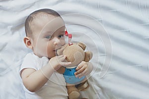 6-8-month-old baby boy lying playfully in bed. Charming 6-7 month little baby in white bodysuit. Baby boy in white bedding. Copy