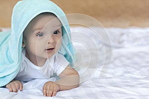 6-8-month-old baby boy lying playfully in bed. Charming 6-7 month little baby in white bodysuit. Baby boy in white bedding. Copy
