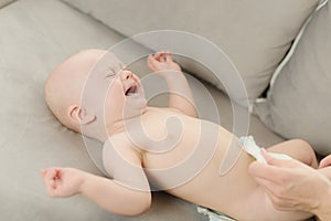 6-month baby boy crying while mother is changing his nappy