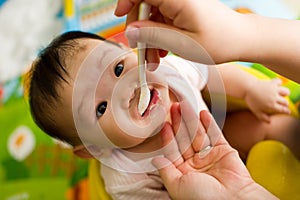 6 month old Asian baby girl being fed cereal