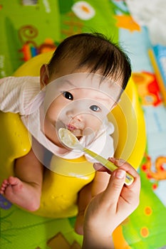 6 month old Asian baby girl being fed cereal