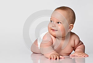 6 month old baby infant lies in one diaper on a light background