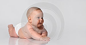 6 month old baby infant lies in one diaper on a light background