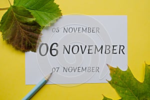 6 november day of month on a white sheet and the dates of the day earlier and later, written in simple pencil. Decoration with
