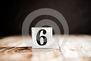 6 - Number 6 - Number Six - White block with number on wooden table and dark background