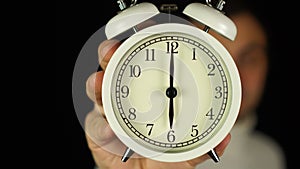 6 o`clock. Human hand holding alarm clock that showing six o`clock and ringing.