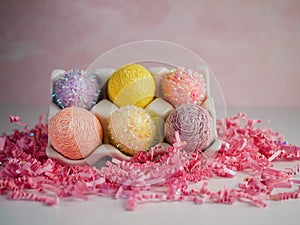 6 String Decorated Easter Eggs in a White Ceramic Holder Sitting on a Bed of Pink Paper Shreds