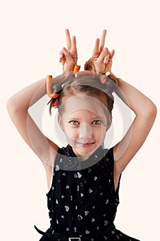 A 6-year-old girl with curlers on her head, fooling around. The pursuit of beauty.Children`s joys. Isolated on a white