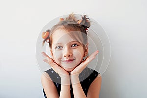 A 6-year-old girl with curlers on her head. The pursuit of beauty.Children`s joys.Isolated on a white background.