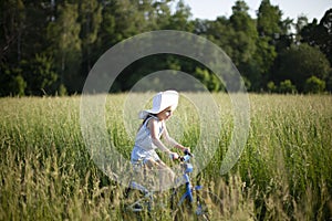 6 year old girl riding a bicycle of a grass covered field.