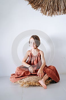 A 6-year-old girl sits on a rug with her legs crossed