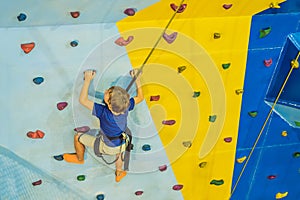 6 years old child climbing on a wall in a climbing center