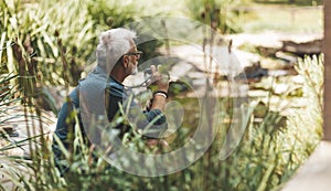 60 year old man in harmony with nature, taking pictures on the lake. Senile depression and loneliness