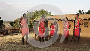 60p wide shot of five maasai warriors dancing at a village near masai mara