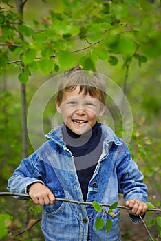 a 7-9-year-old boy in a blue denim jacket walks in the summer forest