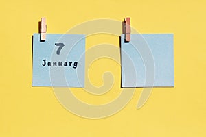 7 January. 7th day of the month, calendar date. Two blue sheets for writing on a yellow background. Top view, copy space. Winter