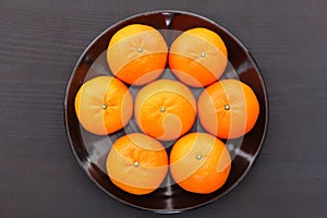 7 orange fruit citrus tankan on black dish against black background