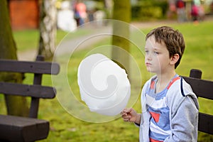 7 years boy eating candy floss in the park