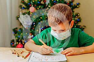 7 years old boy write letter to Santa sitting by desk