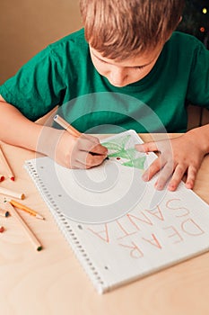 7 years old boy write letter to Santa sitting by desk