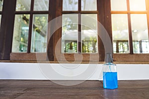 70% Blue Ethyl alcohol gel or hand sanitizer in the plastic bottle on the wooden desk in front of the windows, for coronavirus