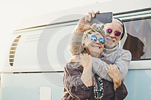 70 years old cheerful happy adult couple take a selfie picture outside a intage blue van with modern technologyh - tourism and