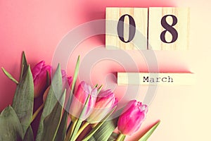 8 March Happy Women`s Day concept. With wooden block calendar and pink tulips on pink background. Copy space