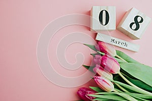 8 March Happy Women`s Day concept. With wooden block calendar and pink tulips on pink background. Copy space