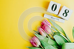 8 March Happy Women`s Day concept. With wooden block calendar and pink tulips on yellow background. Copy space