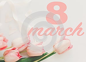 8 march. Happy womens day greeting card. 8 march text on pink tulips with ribbon on white background. Stylish tender image.