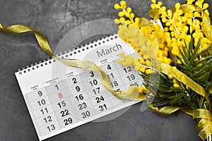 8 March postcard - mimosa flowers with the calendar 8 March on grey concrete background.