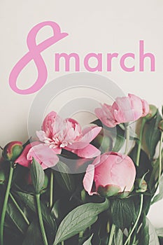 8 March text. 8 march lettering on stylish pink peonies rustic flat lay. Floral greeting card. Happy Women`s day. Beautiful peony