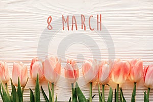 8 march text on pink tulips on white rustic wooden background. g