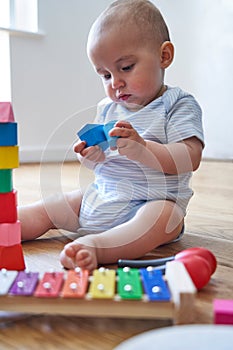 8 Month Old Baby Boy Learning Through Playing With Coloured Wooden Blocks At Home