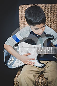 8 year old British Indian boy practices the electric guitar at home.