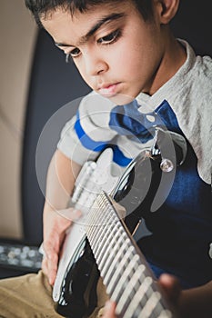 8 year old British Indian boy practices the electric guitar at home.